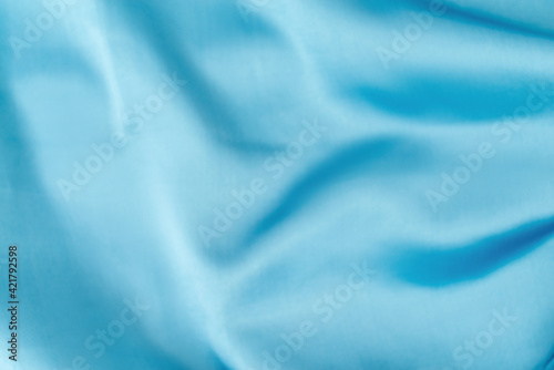 Blue silk fabric defocused for background. Abstract blur satin fabric. Elegant sky color background material with silky satin folds of cloth design