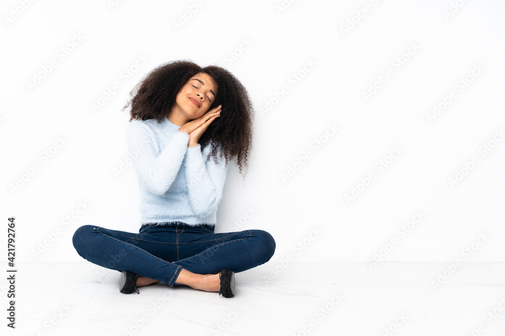Young african american woman sitting on the floor making sleep gesture in dorable expression Young african american woman sitting on the floor making sleep gesture in dorable expression