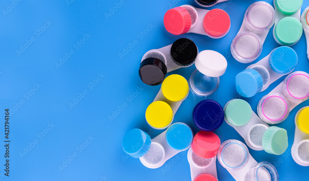 Lots of containers for contact lenses on a blue background. Copy space.