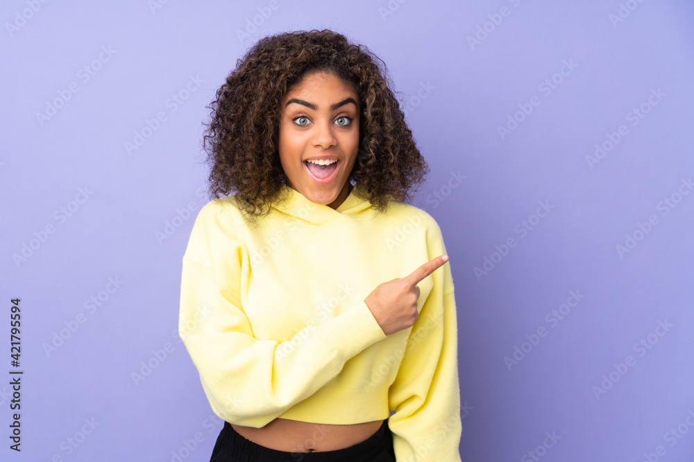 Young African American woman isolated on background surprised and pointing side Young African American woman isolated on background surprised and pointing side