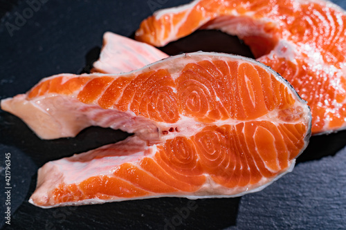 A piece of raw fish on a dark metallic background. Close-up. Fish meal.