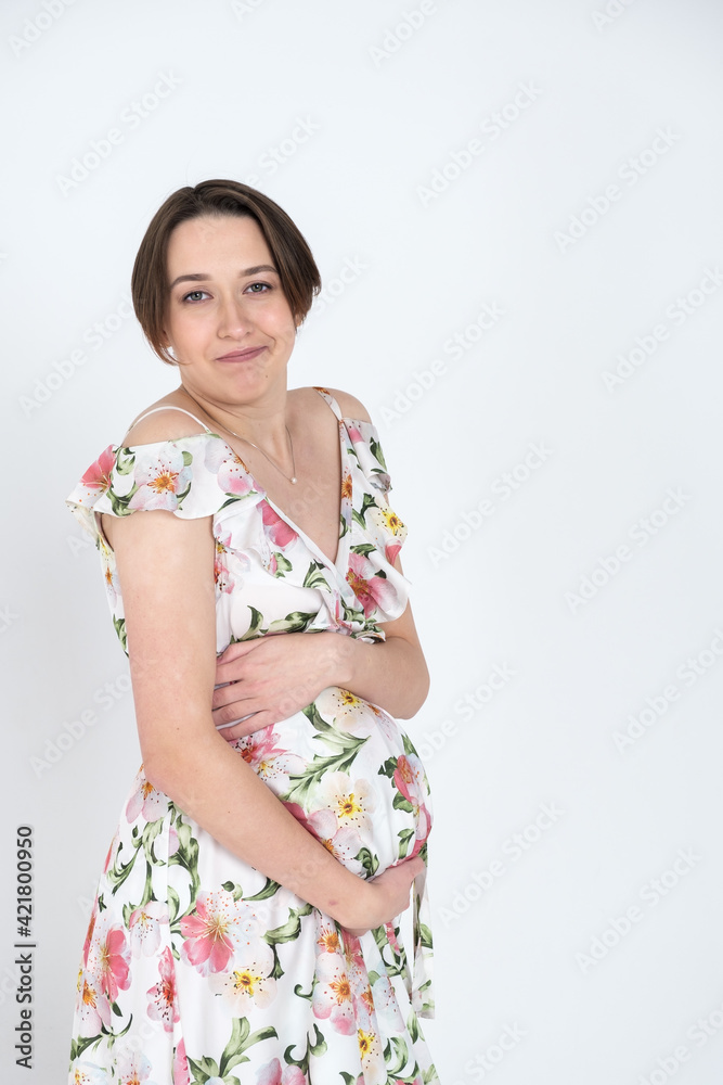 Studio portrait of cheerful young pregnant woman in summer dress on white gray background, happy pregnancy concept Studio portrait of cheerful young pregnant woman in summer dress on white gray background, happy pregnancy concept