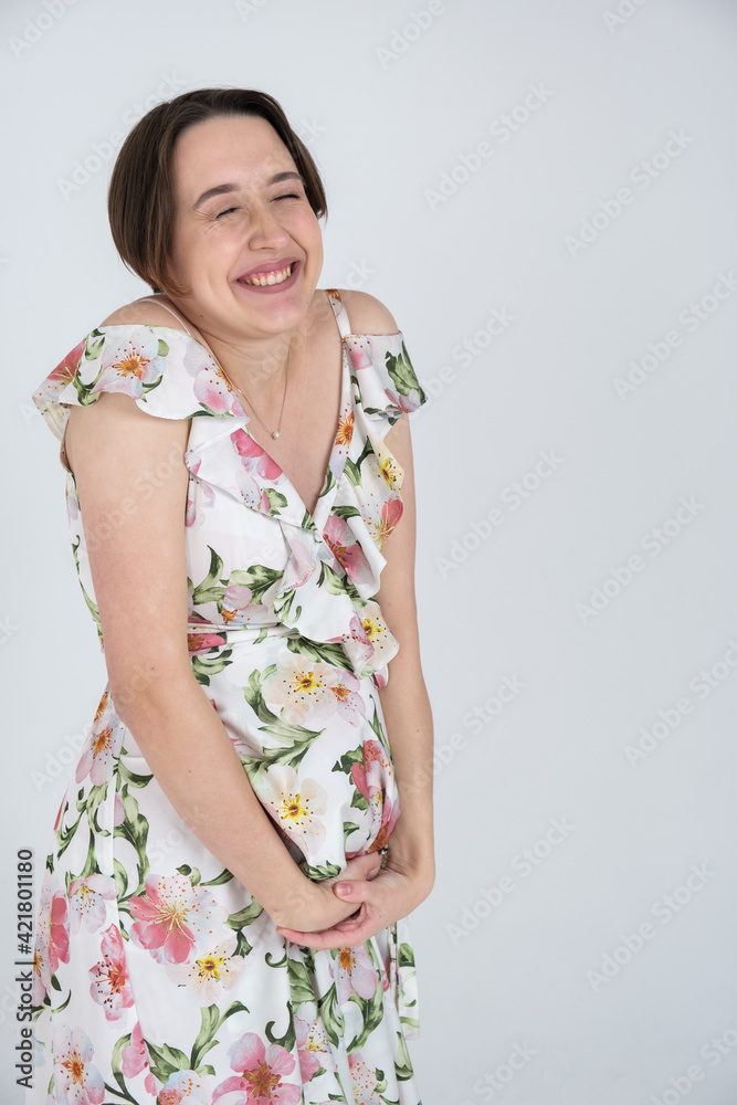 Studio portrait of cheerful young pregnant woman in summer dress on white gray background, happy pregnancy concept