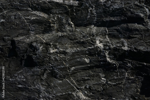 Black rough stone wall texture for background or wallpaper. © Natt