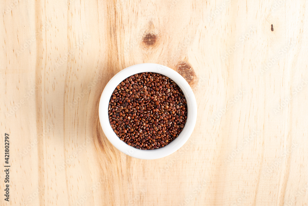 Red quinoa in white bowl on wood Red quinoa in white bowl on wood