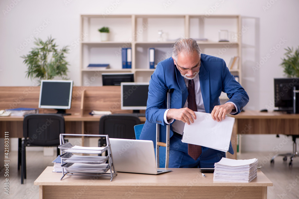 Old businessman employee after accident working in the office Old businessman employee after accident working in the office