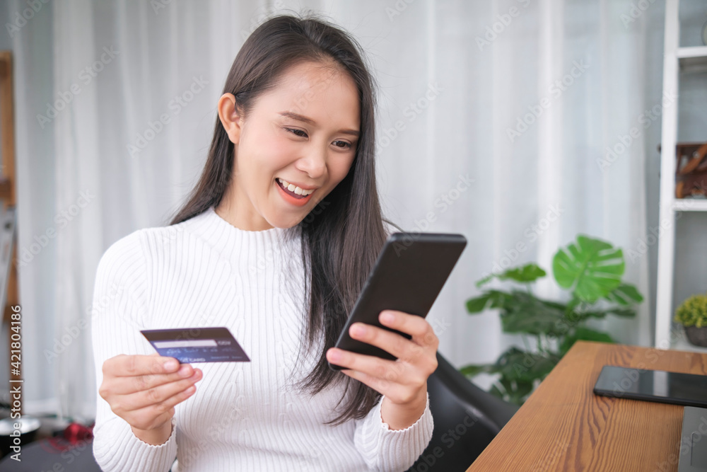 Young Asian business woman using online payment digital money currency transaction purchasing product online using credit debit card cash transfer mobile smartphone bank app, home living lifestyle Young Asian business woman using online payment digital money currency transaction purchasing product online using credit debit card cash transfer mobile smartphone bank app, home living lifestyle