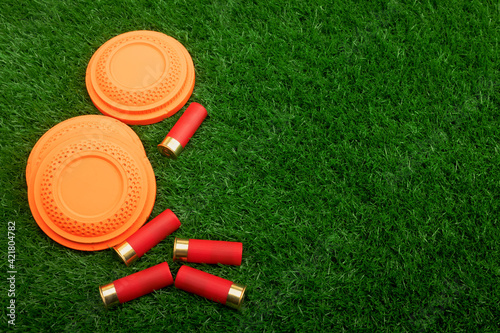 Clay disc flying targets and shotgun shells on artificial grass background ,Clay Pigeon target
