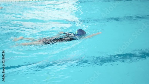 An Asia boy wearing goggles and cap jump from the floor in the swimming pool and do freestyle. Summer and vacation. Learning with professional in the school. Enjoy and happy with class.