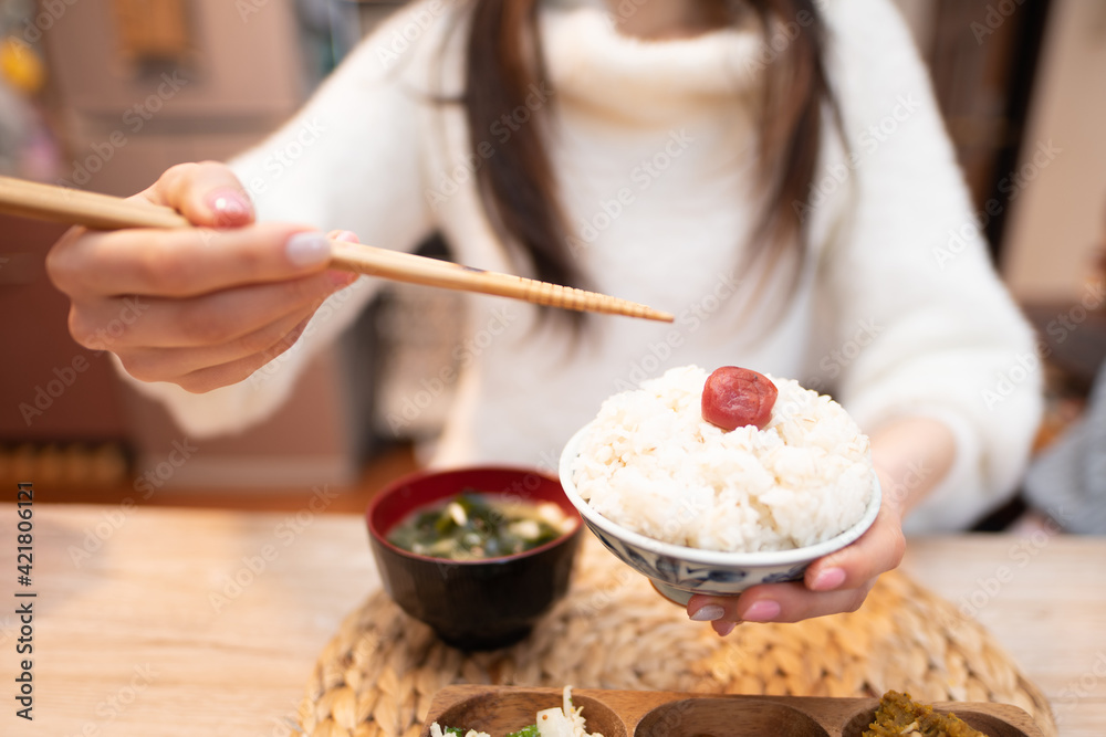 お茶碗に入ったお米を食べる女性