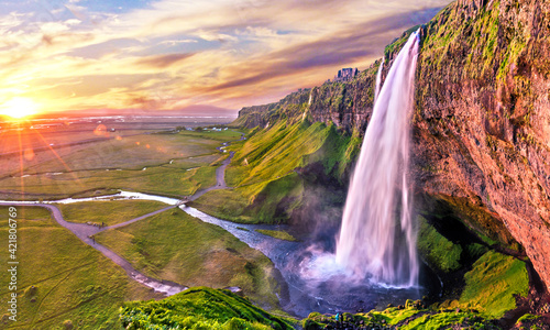 Obraz na płótnie Charming beautiful waterfall Seljalandsfoss in Icelandat sunset. Exotic countries. Amazing places. Popular tourist atraction. w salonie