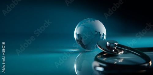 World Health Day. Global Health Care Concept. Transparent Glass Globe and Stethoscope lay on Blue background. Modern and Digital Technology Color Tone. Wide and Long size