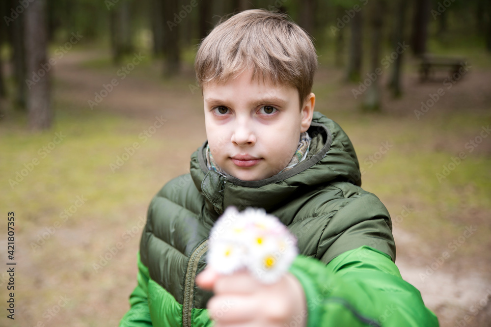Mothers day theme. Boy holding bunch of meadow sunshine flowers. Spring celebration bouquet. Picture in the forest. Early flowers. Emotional present. Mothers day theme. Boy holding bunch of meadow sunshine flowers. Spring celebration bouquet. Picture in the forest. Early flowers. Emotional present.