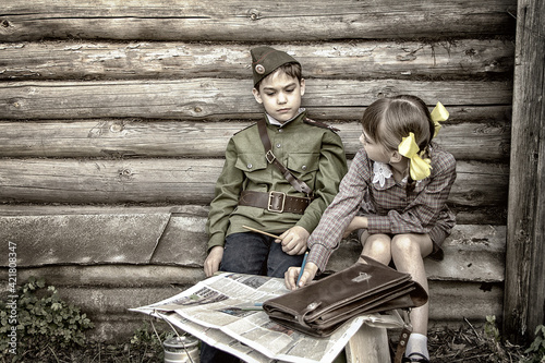 Postcard, stylized as vintage for the Victory Day. A boy in a military uniform and a girl in an old dress. The theme of May 9, Victory Day in Russia. Soft selective focus, added noise. photo