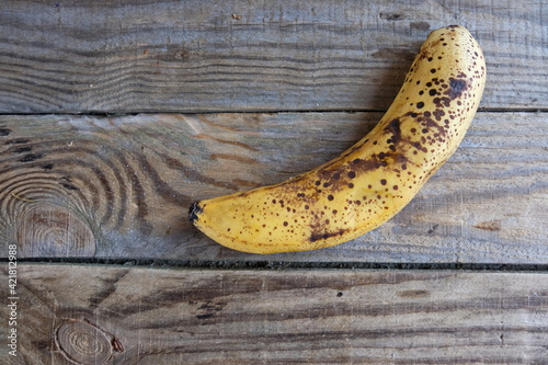 Overripe banana with dark spots on the skin . Ugly fruit. Buying imperfect products is a way to deal with food waste. Horizontal.