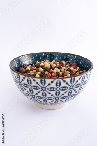 five pepper seeds on blue bowl isolated