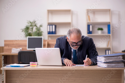 Old male employee auditor wearing many glasses at workplace