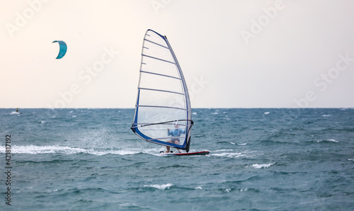 The sail on the board floats in the sea.