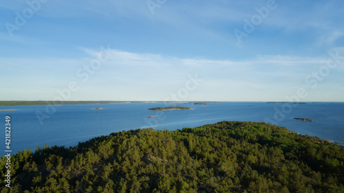 Aerial top view of blue sea with islands and green pine trees in Finland at sunset. Beautiful summer landscape.