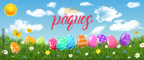 carte ou bandeau sur Joyeuse Pâques en jaune et rouge avec dans l'herbe des oeufs et des fleurs et sur un fond de ciel bleu avec des nuages