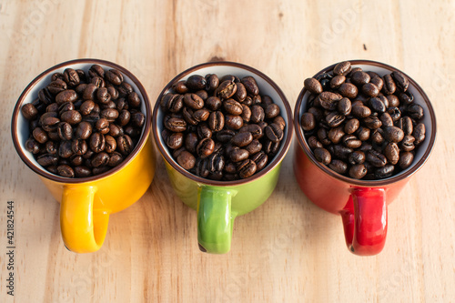 red, green, yellow cups with coffee beans on wood