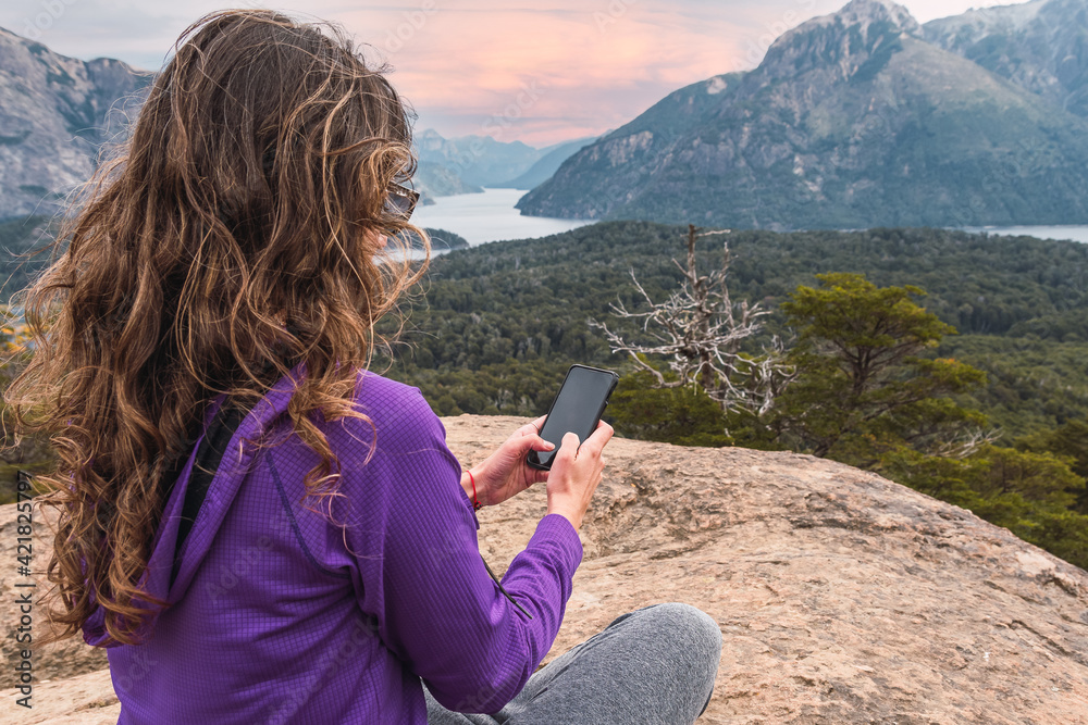 latin woman with cell phone in mountainous landscape