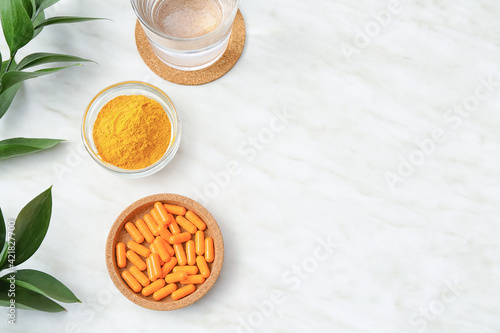 Bowls with turmeric pills and powder on light background
