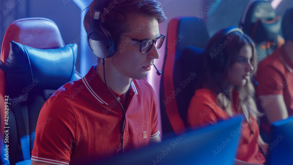 Professional Gamer Plays Computer Video Game Talking into Headset with Teammates on a Championship. Esport Team of Pro Gamers Play in Computer Game. Stylish Neon Cyber Games Arena. Portrait View Professional Gamer Plays Computer Video Game Talking into Headset with Teammates on a Championship. Esport Team of Pro Gamers Play in Computer Game. Stylish Neon Cyber Games Arena. Portrait View