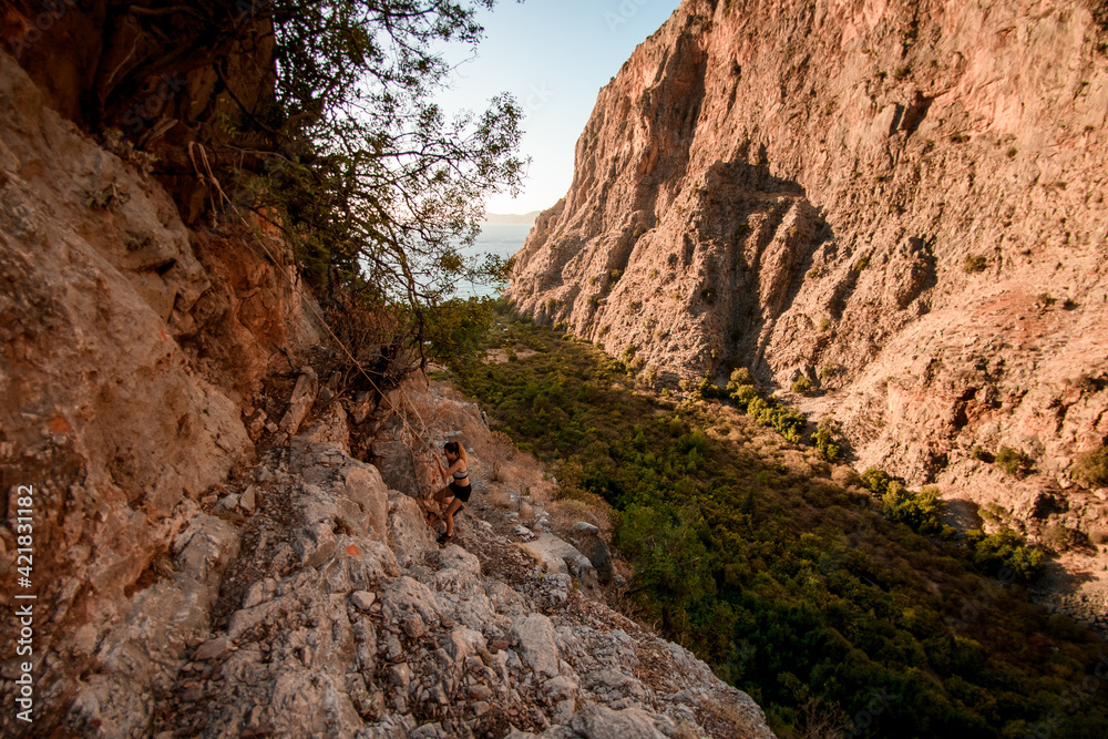 high angle view on athletic woman who climbing up on mountain rocks using rope.