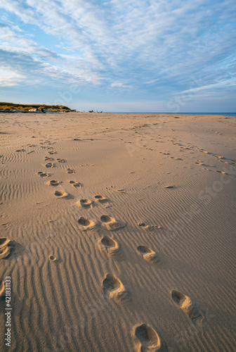 Footprints in the sand with a blue sky and white clouds in the background. Coastline of the Baltic Sea near Carnikava, Latvia