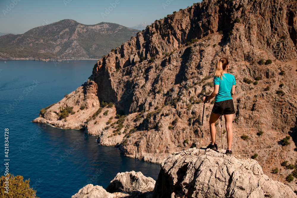 rear view of woman standing on large stone and enjoying view of sea bay rear view of woman standing on large stone and enjoying view of sea bay