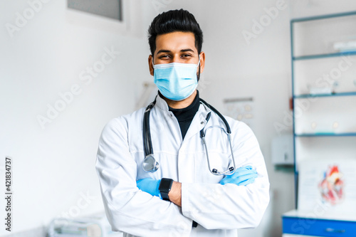 A young Indian doctor in a protective mask and gloves with a stethoscope on among a modern hospital  Indian medicine  health and self-care