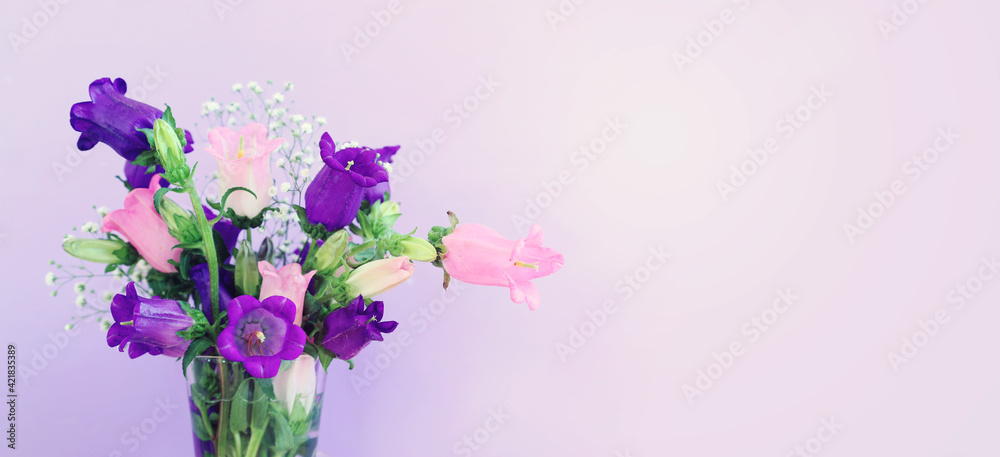 Naklejka premium spring bouquet of purple and pink bell flowers over purple wooden background