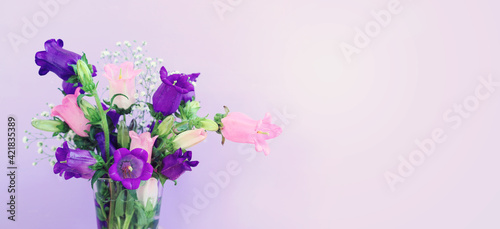 spring bouquet of purple and pink bell flowers over purple wooden background