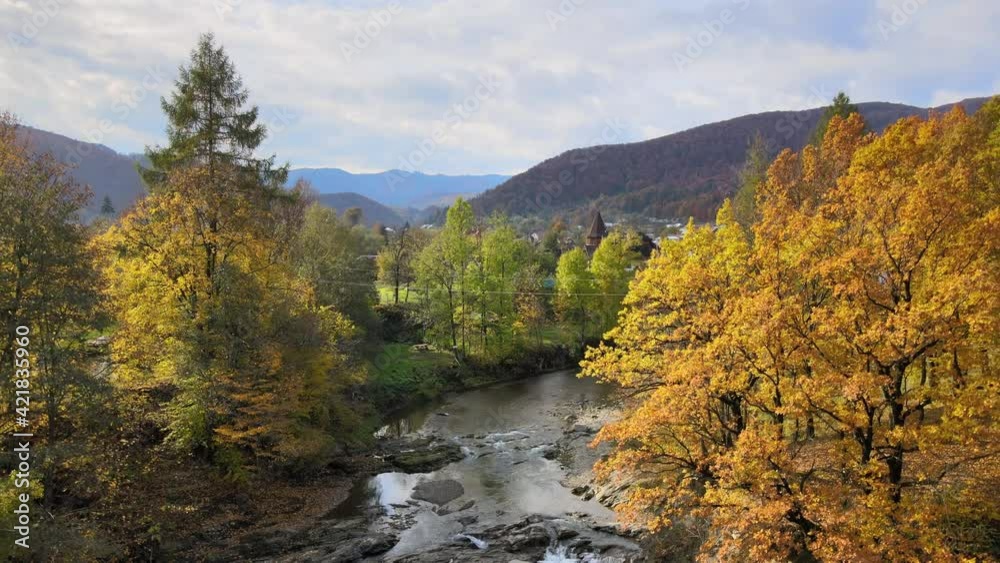 Aerial view of a rural village with small houses between autumn mountain hills covered with yellow and green pine trees. Aerial view of a rural village with small houses between autumn mountain hills covered with yellow and green pine trees.
