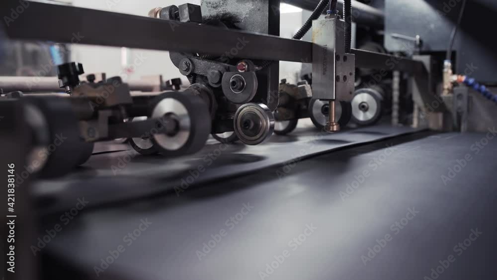 Modern automatic conveyor line for the production of package. Cardboard manufacturing layering rollers roll industrial industry printing packaging material closeup. Enterprise for production package Modern automatic conveyor line for the production of package. Cardboard manufacturing layering rollers roll industrial industry printing packaging material closeup. Enterprise for production package