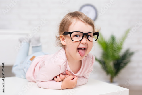 cute little girl in big glasses having fun and showing tongue