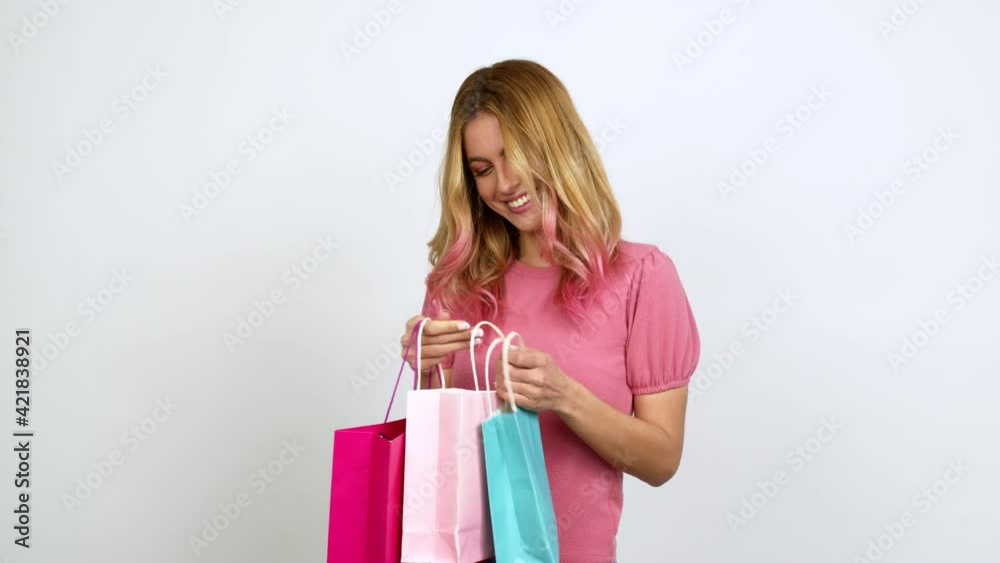 Young blonde woman holding shopping bags and surprised isolated on background Young blonde woman holding shopping bags and surprised isolated on background