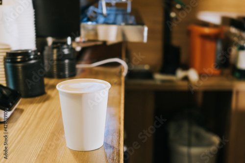 A paper coffee cup is on the counter in a coffee shop. Morning concept, coffee to go.