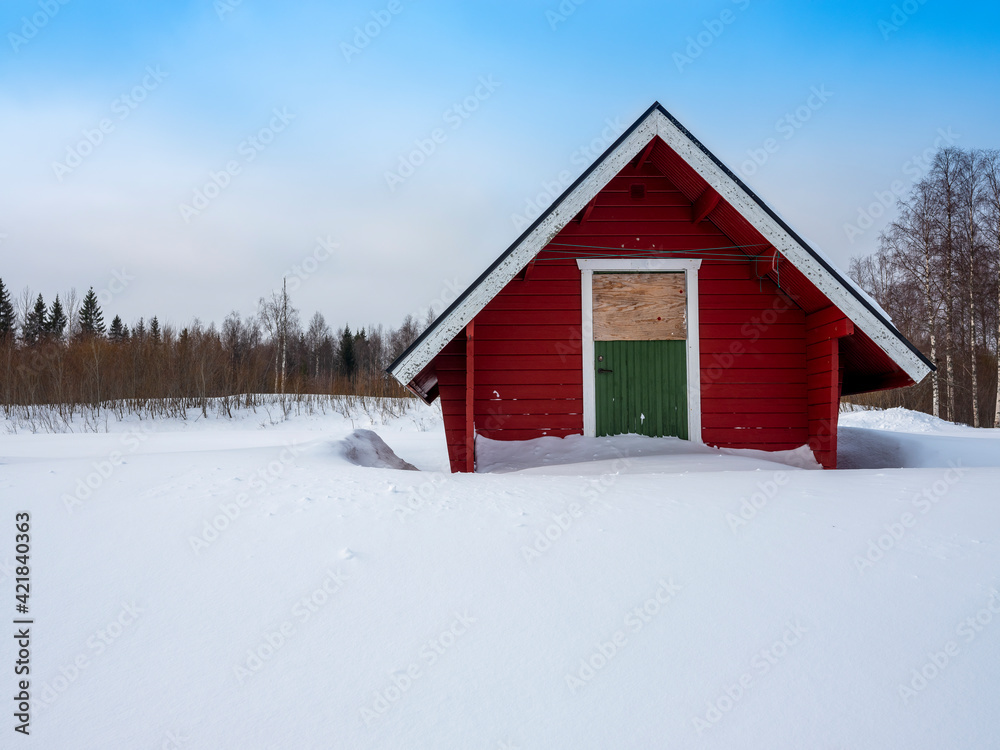 A small wooden shed standing on pure white snow on a sunny winter day. A small wooden shed standing on pure white snow on a sunny winter day.