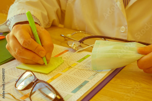 Physician working with paper in hospital office. Therapeutist sitting at working table making some paperwork