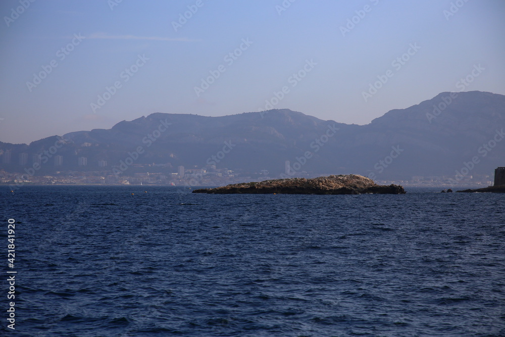 The expanse of the sea with rocks in the foreground and the city on the coast in the background, Parc National des Calanques, Marseille, France