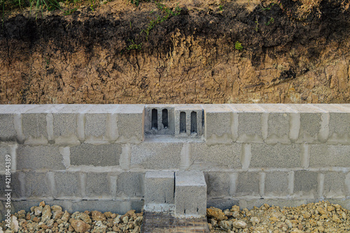 Construction of stone walls of a building from hollow concrete blocks on heavy granite gravel. Masonry walls made of heavy concrete blocks. Front view. photo