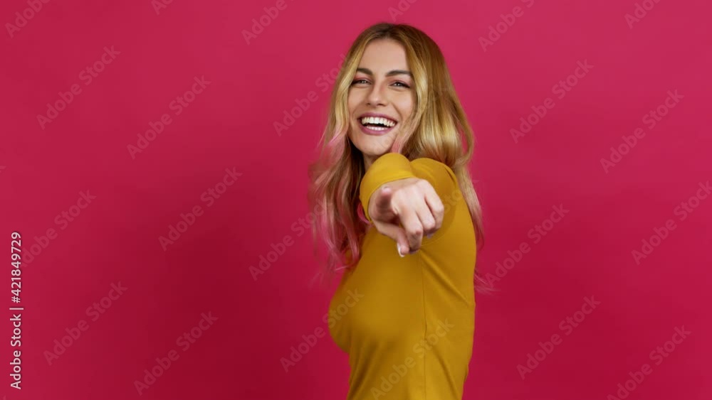 Young blonde woman points finger at you with a confident expression over isolated background Young blonde woman points finger at you with a confident expression over isolated background