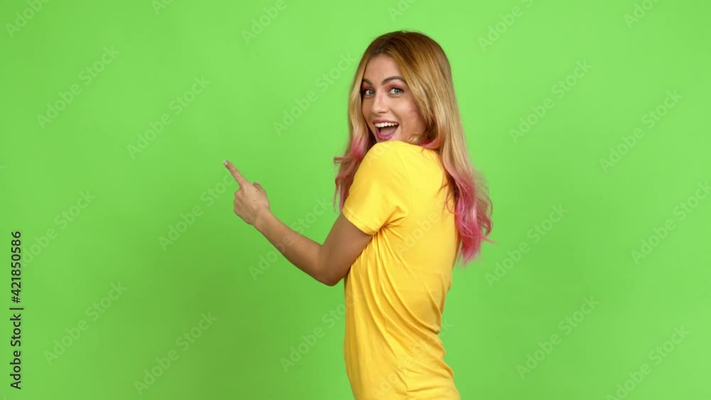 Young blonde woman pointing back and presenting a product over isolated background on green screen chroma key Young blonde woman pointing back and presenting a product over isolated background on green screen chroma key