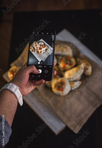 Celular fotografiando empanadas caseras para redes sociales photo