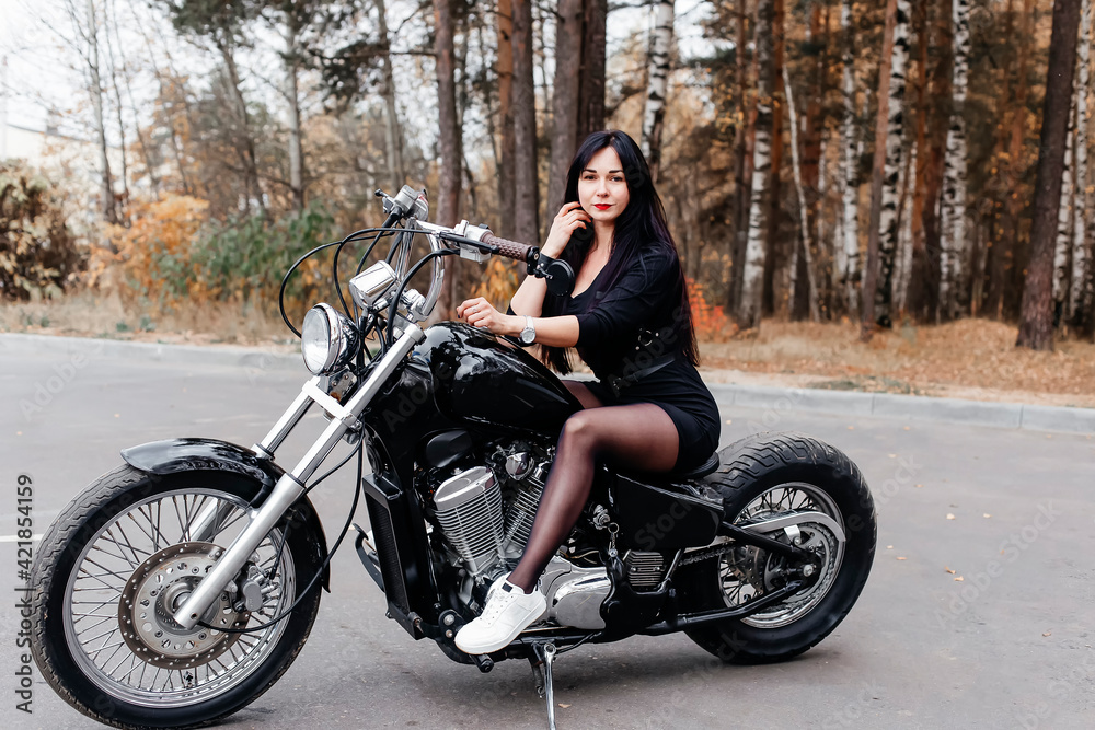 beautiful brunette in a dress on a motorcycle in the park