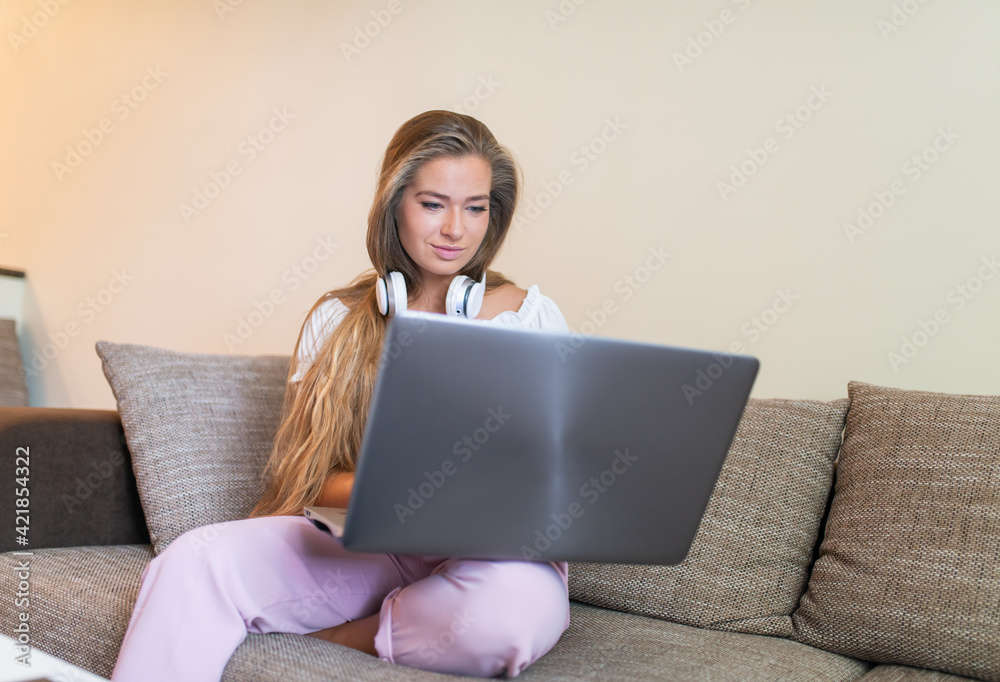 Woman using a laptop while relaxing on the couch Woman using a laptop while relaxing on the couch