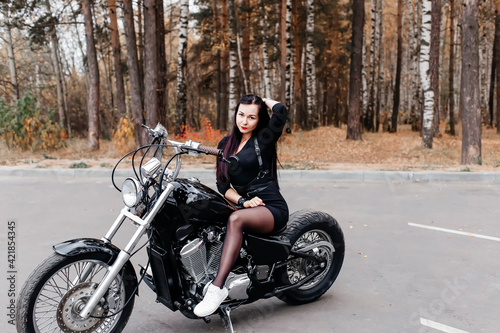 beautiful brunette in a dress on a motorcycle in the park