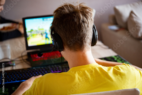 ragazzo con maglietta gialla che gioca con videogames su pc con cuffie e microfono photo